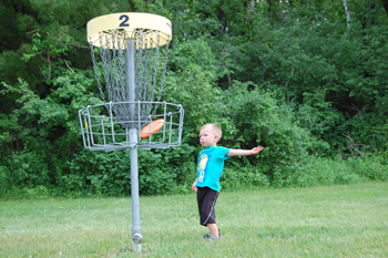小男孩打光盘高尔夫球