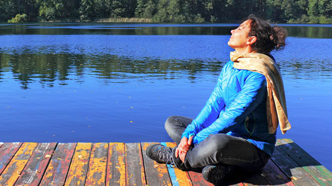 坐在湖船坞的妇女交叉腿,浸泡太阳