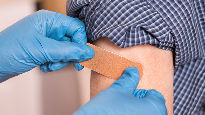 戴手套的手在手臂上包扎绷带